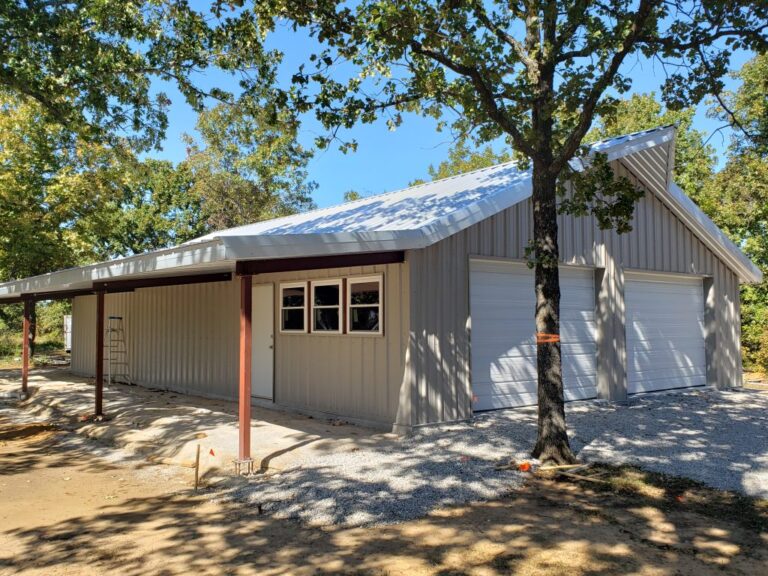 Large metal garage building among trees.